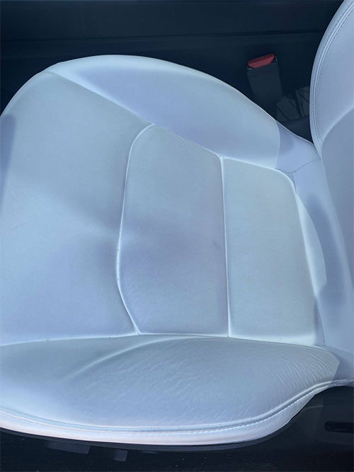 Image of white tesla seat stained from blue fabric dye